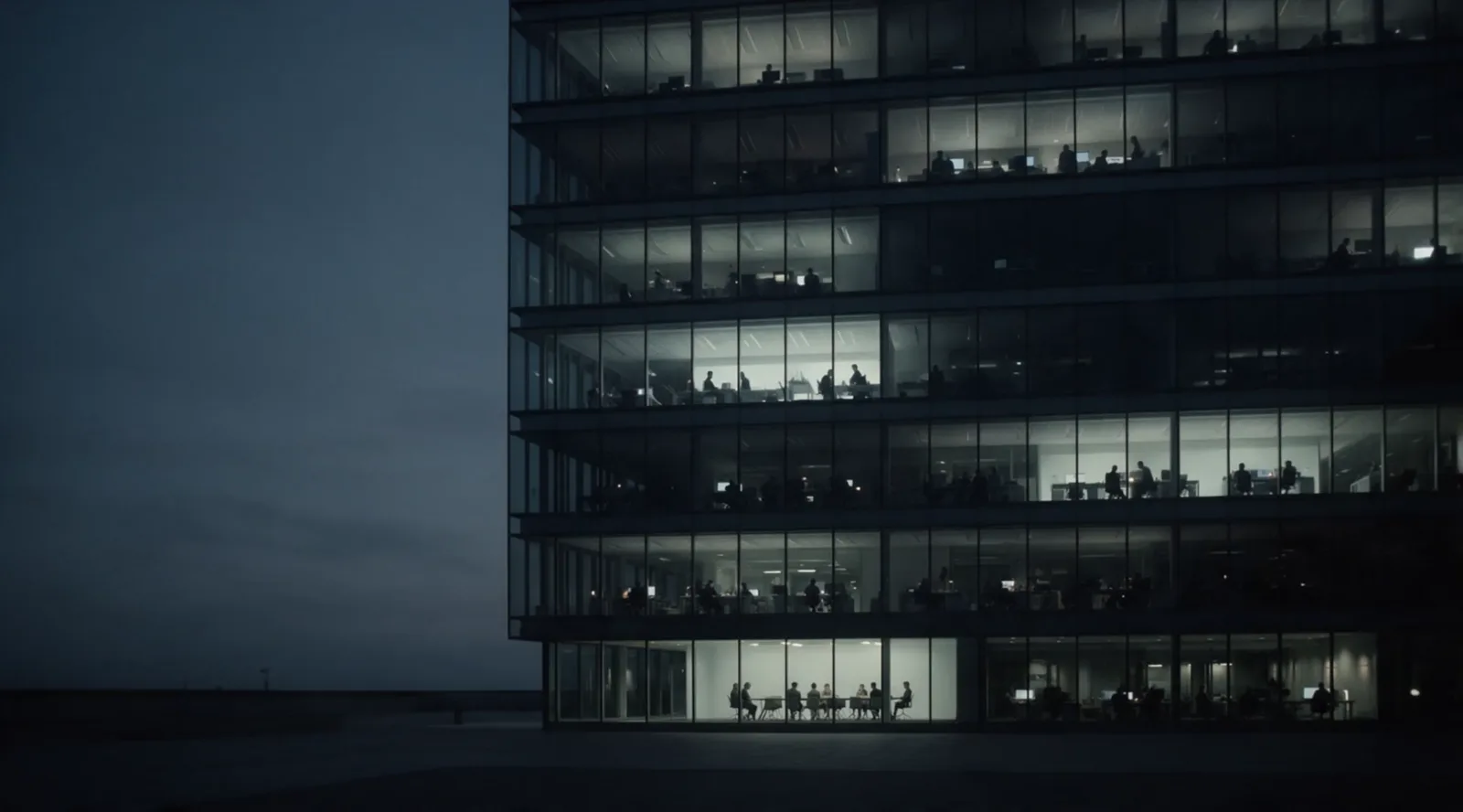 A company headquarters at blue hour, its office floors lit